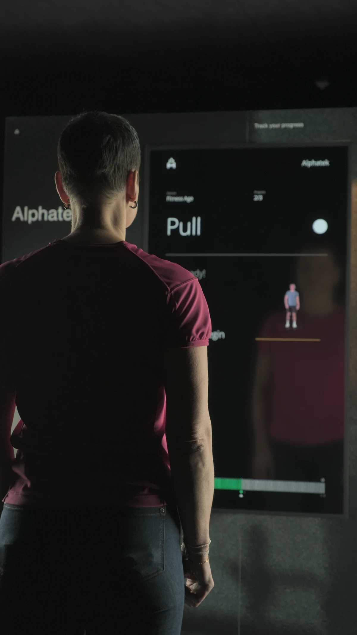 A participant facing the Alphatek display showing Pull in Fitness Age.