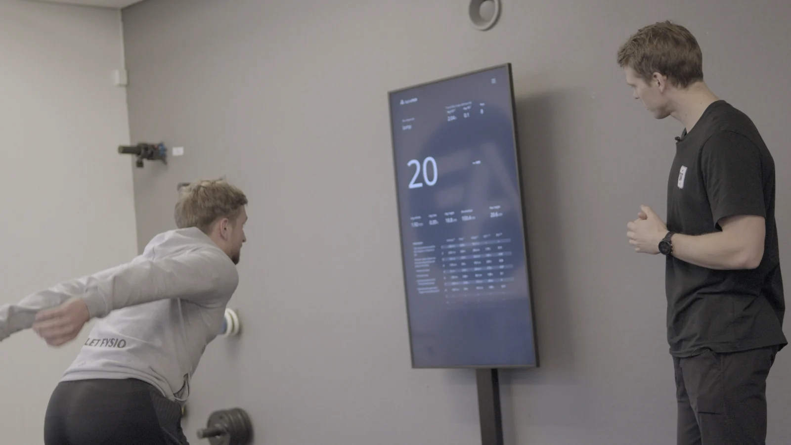 A user performs a test in front of the Alphatek display while a coach observes.