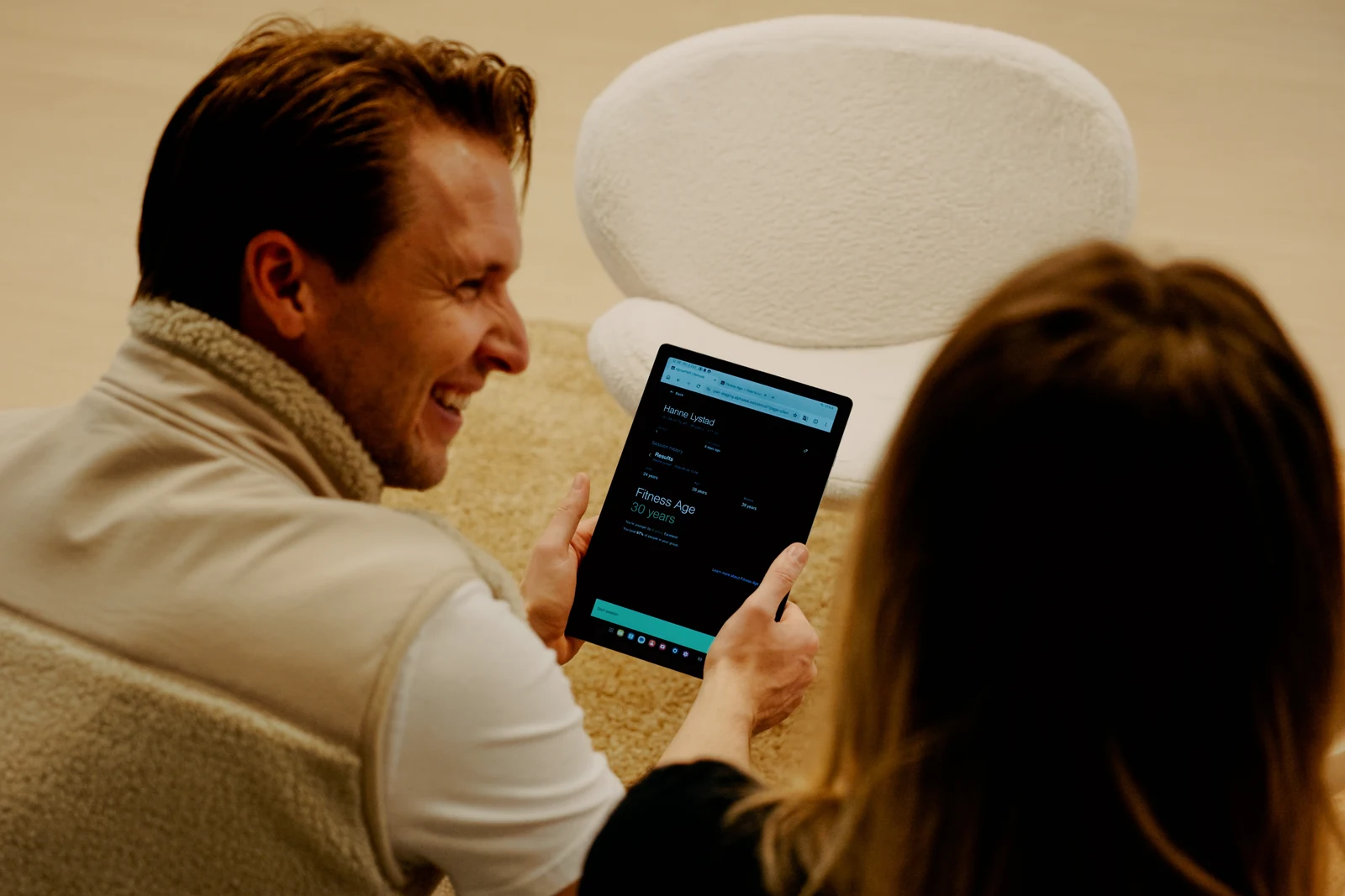 A trainer and member review Fitness Age results on a tablet.