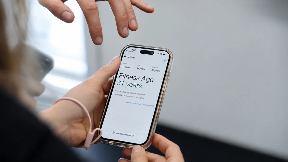 A member and trainer review Fitness Age results on a phone.