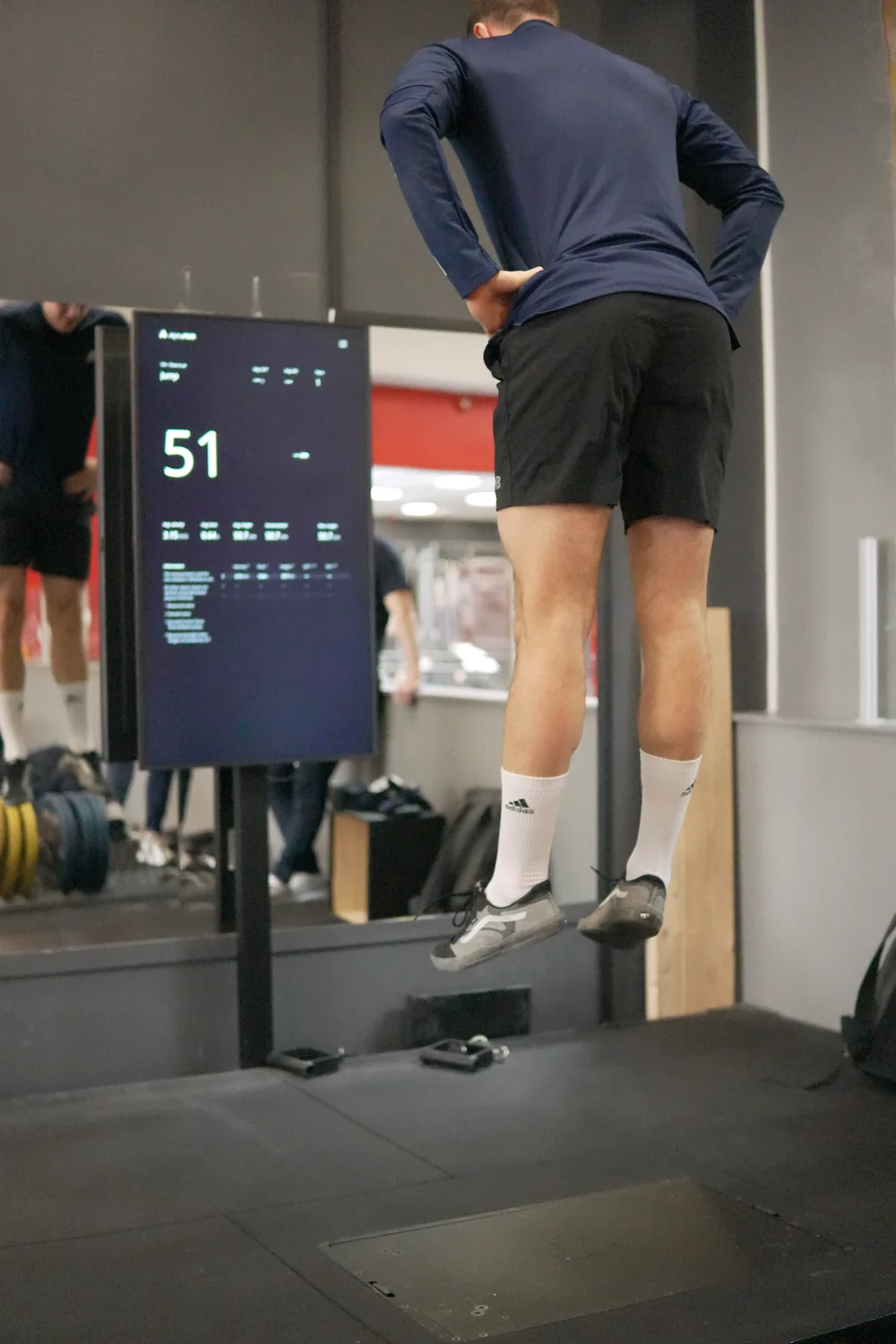 An athlete jumping above the Alphatek platform, with the result display to the left.