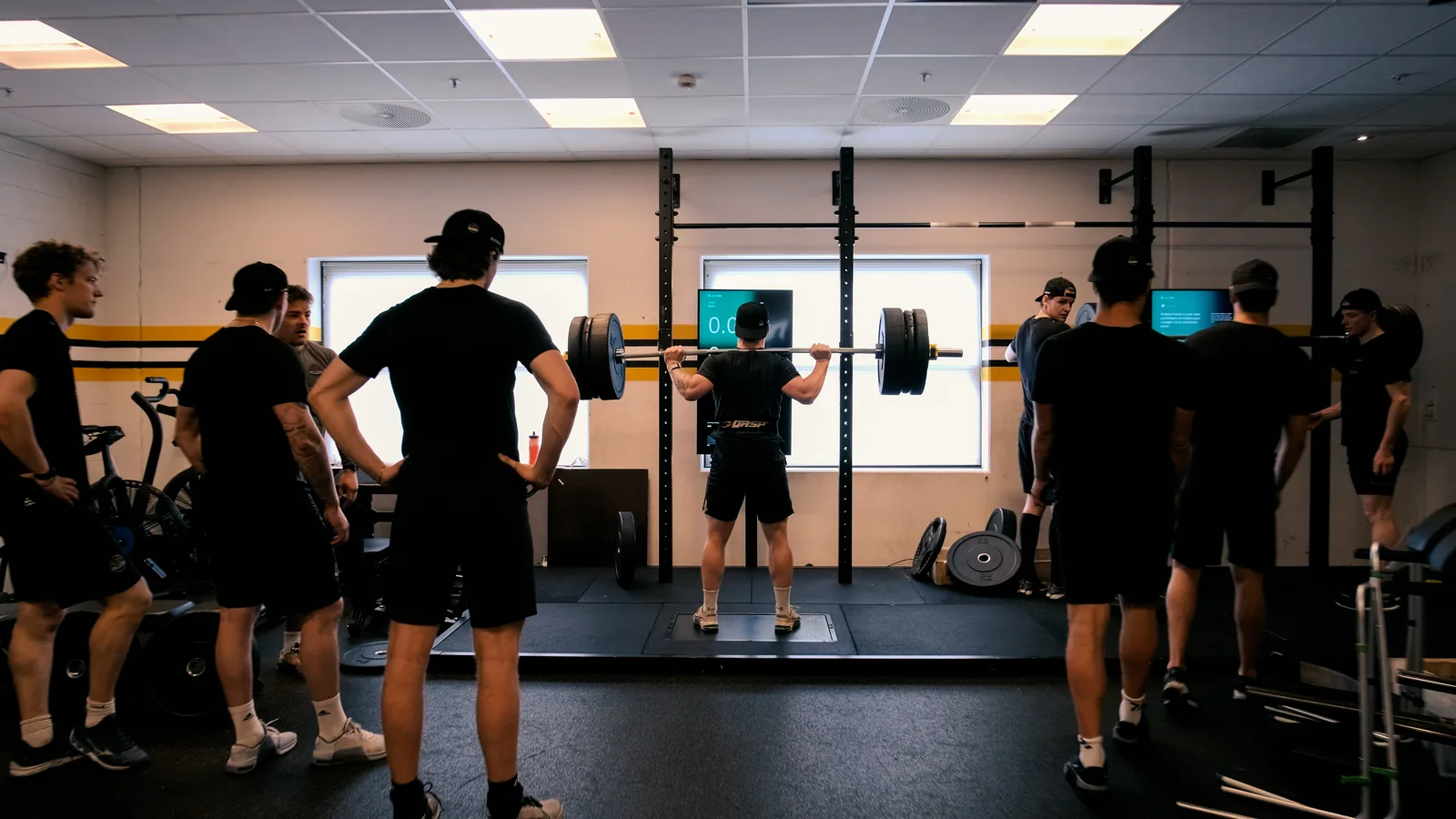 An athlete performs a squat on the Alphatek platform while others observe.