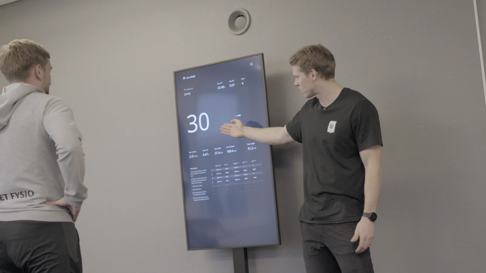 Two people review an Alphatek result together while one explains the display.