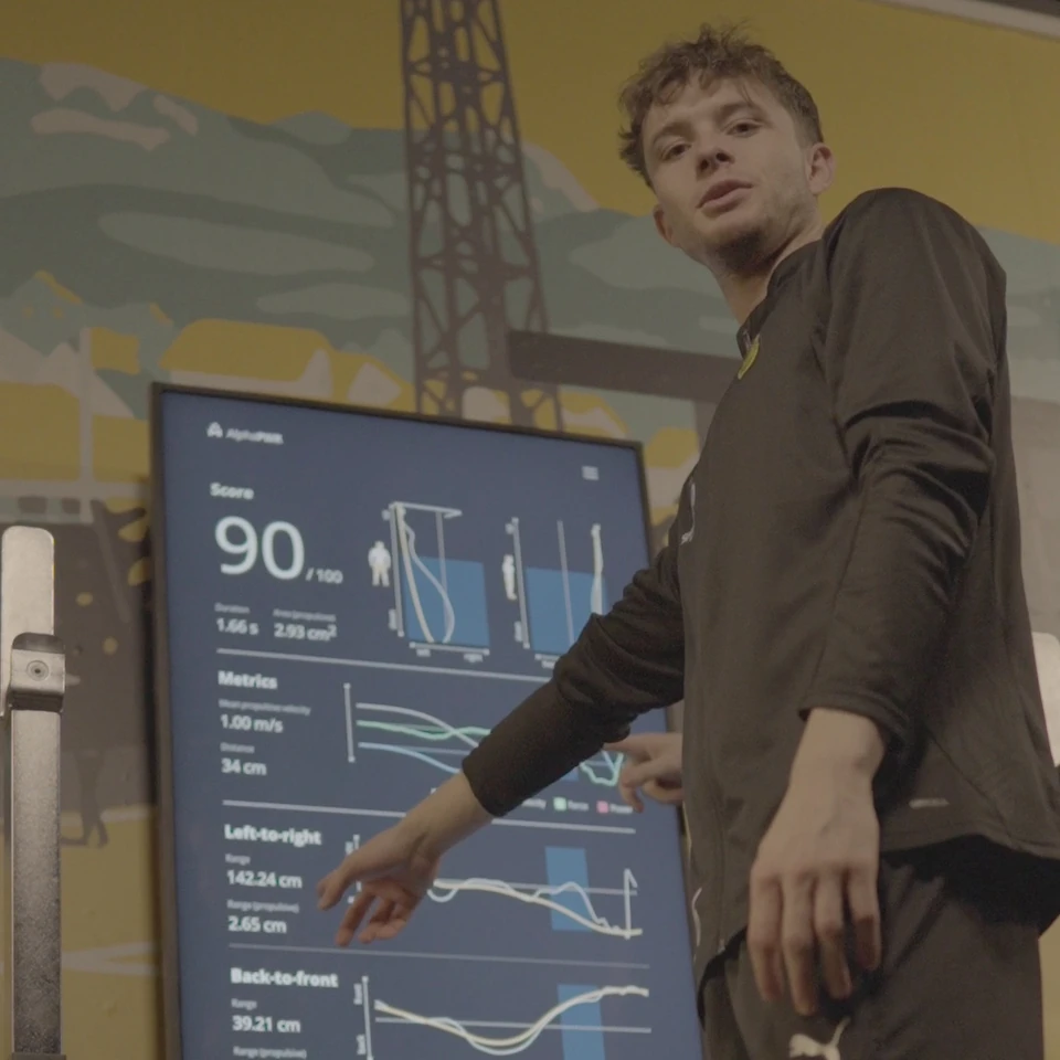 An athlete points to measurement curves on the Alphatek display.